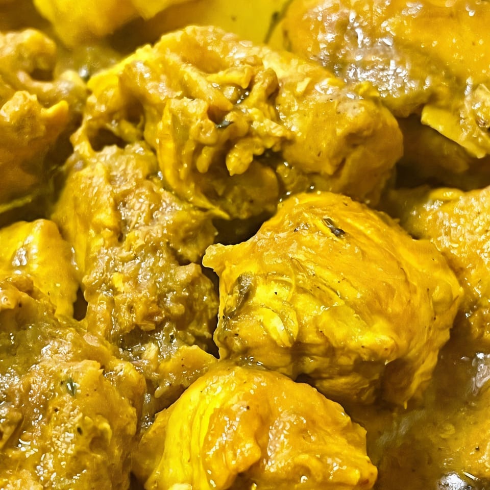 Close-up of Hellshire Cuisine's Jamaican curry chicken, featuring tender pieces in a rich yellow sauce.